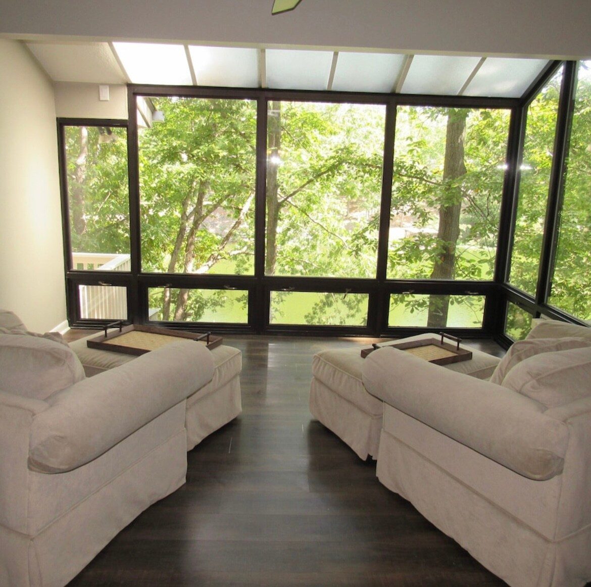 Bright glass sunroom with wraparound windows overlooking the lake and woods